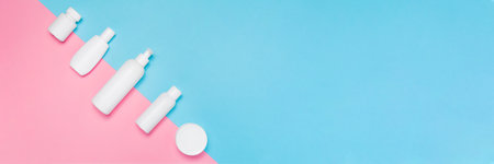 Banner with white cosmetic bottles mockup on pink and blue background. Tubes, dispensers and jars. Branding identity concept. Flat lay with copy spaceの写真素材