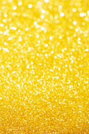 Abstract golden yellow and orange glitter lights background. Circle blurred bokeh. Festive backdrop for Christmas, holiday or eventの写真素材