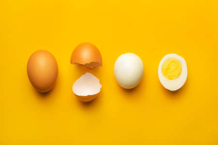 Fresh farm brown chicken boiled egg creative layout and composition on yellow background. Minimalistic healthy food concept. Top view, flat layの写真素材