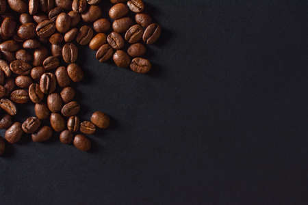 Fresh roasted coffee beans closeup on black stone background. Top view, flat lay with copy space