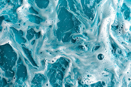 White soap foam with bubbles texture on blue background. Detergent foam bubble on water, soap sudの素材