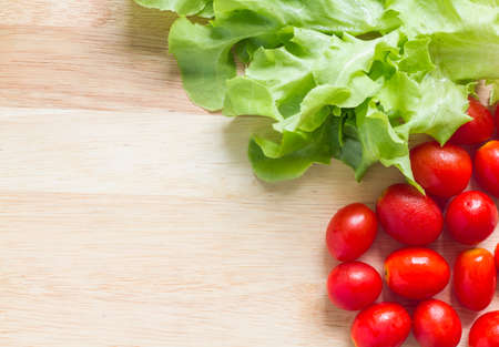 Fresh green oak leaf and cherry tomatoes on wooden backgroundの写真素材