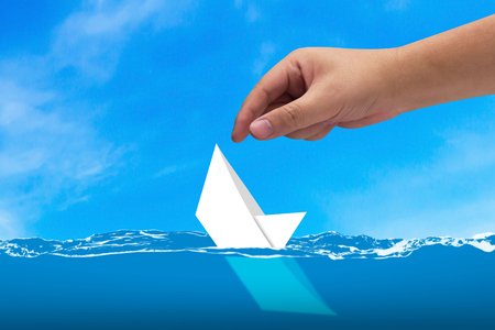 Business solution, solving problem, strategy and planning concept, hand rescue sinking paper boatの写真素材