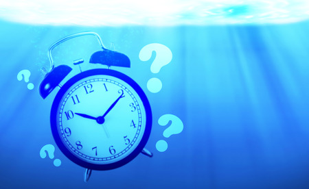 Time management concept, business planning, alarm clock drowning in the sea