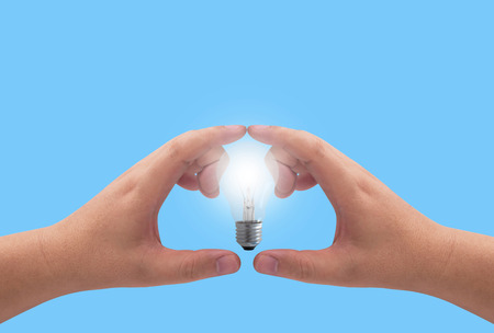 Idea and inspiration concept, business creativity, hand holding light bulb on blue background with copy spaceの写真素材