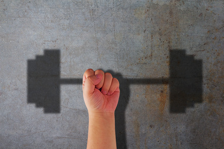 Strong and strength concept, hand and dumbbell shadow on concrete backgroundの写真素材