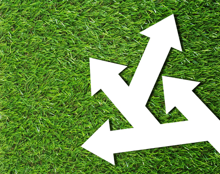 Business problem or confused concept, white arrow on green grass backgroundの写真素材