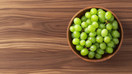 Top-down view of juicy green grapes in a deep wood bowl, surrounded by natural table grain patternsの素材