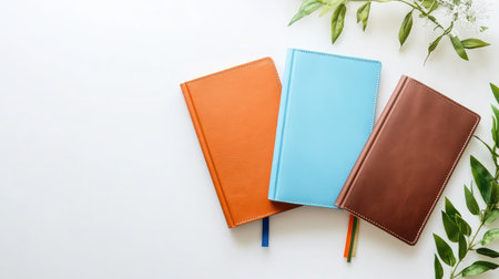Stylish flatlay of three colored leather-bound journals in bold yet classic hues--blue, orange, and brownの素材