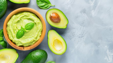 A vibrant and creamy avocado dip served in a rustic wooden bowl, surrounded by fresh avocados and fragrant basil leaves, perfect for healthy snacking.の素材