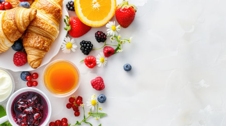 A vibrant breakfast spread featuring flaky croissants, fresh berries, and citrus fruits arranged artfully on a light background. Perfect for morning meals.の素材