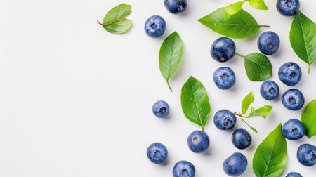 A vibrant display of fresh blueberries and green leaves arranged on a clean white background, highlighting the healthy and natural aspects of fruit.の素材