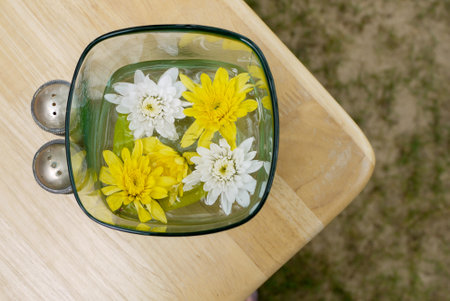 Flowers in the cup of water put on the wood tableの写真素材