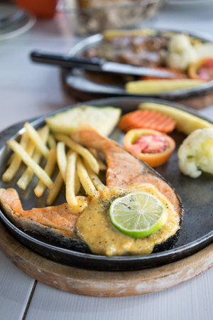 Salmon steak with iron plate on dinning tableの写真素材