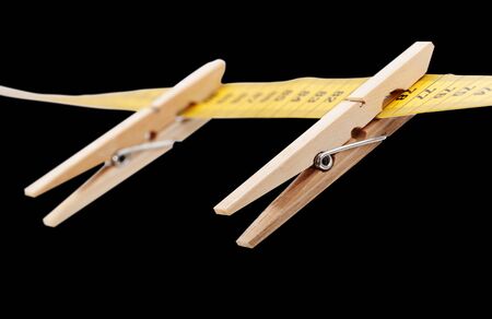 Clothespins and measuring tape isolated on a black surface.