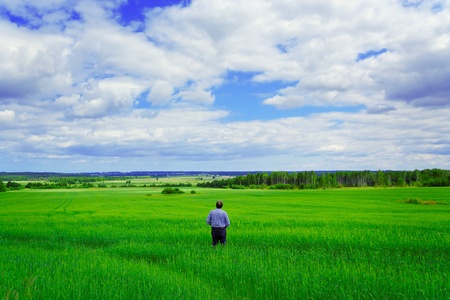 Man staying on the green wheat field.