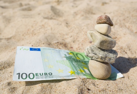 100 euro and stack of stones on the sand の写真素材