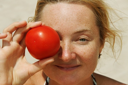 Freckled young woman with tomato.の写真素材