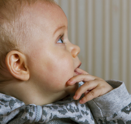 Growing infant with finger in mouth.の写真素材