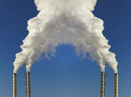Smoke from chimneys on blue sky .