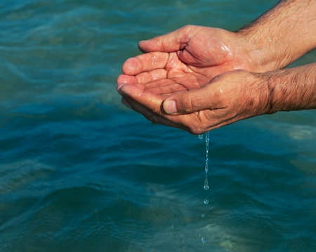Photo of hands with sea water.の写真素材