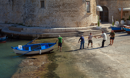 ITALY, GIOVINAZZO - OCTOBER 6: Five men pull one boat to the shore of the pier Giovinazzo in a morning, what is located on the Adriatic sea coast. Giovinazzo on 6 October 2017, Italy.のeditorial素材