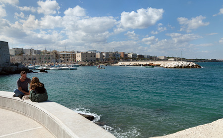 ITALY, GIOVINAZZO - OCTOBER 6: Giovinazzo is located on the Adriatic sea coast. Pair on mole in a morning on 6 October 2017,Giovinazzo, Italy.のeditorial素材