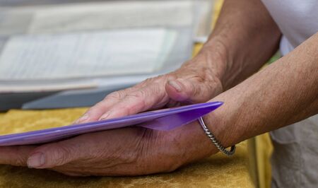 Hands of a female elderly with paper on a table.の写真素材