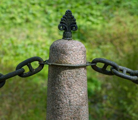 Old column with metal chain on road to the old castle.