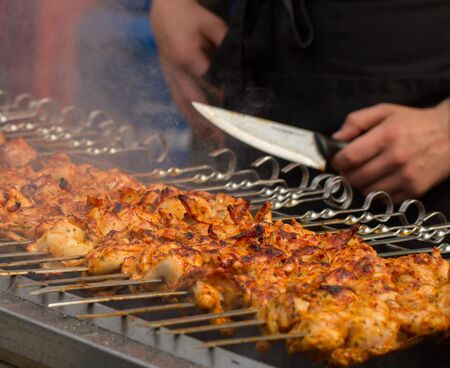 Young man preparing meats on barbecue.
