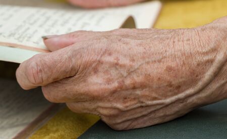 Hands of a female elderly with paper on a table.の写真素材