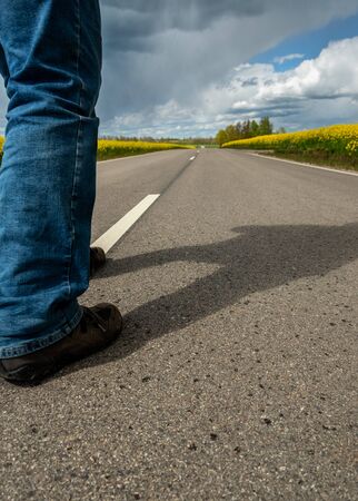 Man on asphalt road beatween canola fields.の写真素材
