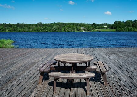 Picnic table on wooden platform ar the river.