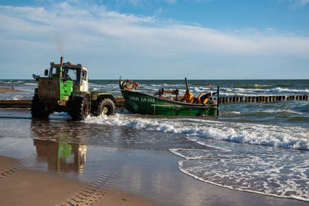 LATVIJA, JURMALCIEMS - JULY 9: Best fishing in the Baltic sea. Tractor towing fishing boat from water on 9 July 2020, Jurmalciems, Latvia.のeditorial素材