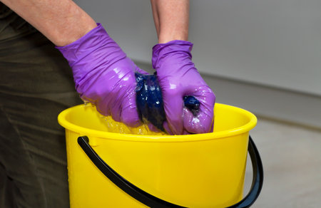Woman squeezes the floor cloth into the yellow bucket.の写真素材