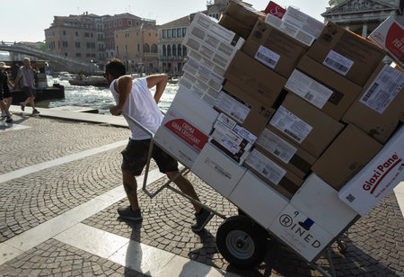 ITALY, VENICE - JUNE 16: Venice is a city in the northeast of Italy.  View of a worker with a heavy load on June 16, 2022, Venice, Italy.のeditorial素材