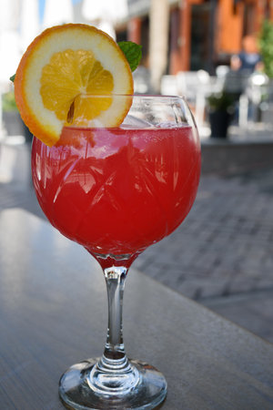 Red cocktail with slice of orange on the wooden table in outside cafe.の写真素材