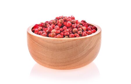 dried pink peppers in wood bowl on white backgroundの写真素材