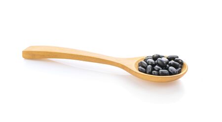 Black beans in wooden spoon isolated on white background.の写真素材