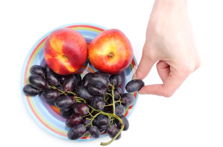Hand with grapes and nectarines on the color plate isolated on white backgroundの写真素材