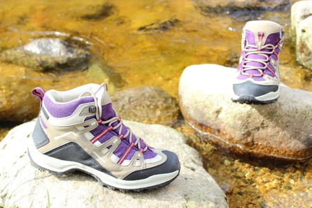 Pair of hiking boots over a mountain stream