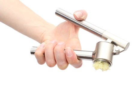 Hand of woman using a garlic press, squeezing fresh and natural garlic  Isolated on white backgroundの写真素材