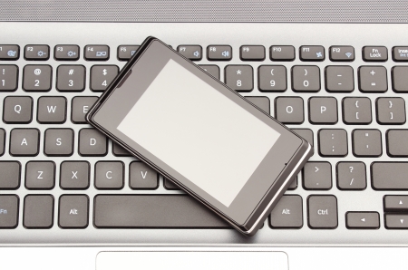 Mobile phone lying on the laptop keyboardの写真素材