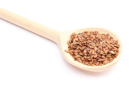 Heap of brown linseed on wooden spoon  Isolated on white backgroundの写真素材