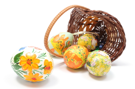 Closeup of colorful painted Easter eggs in overturned wicker basket, Easter decoration  Isolated on white の写真素材