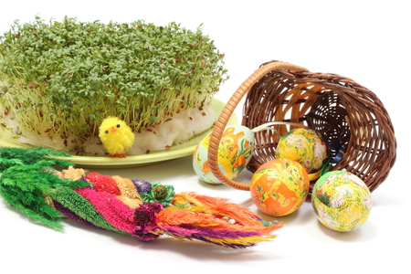 Closeup of colorful Easter palm, colorful painted Easter eggs in overturned wicker basket and fresh...