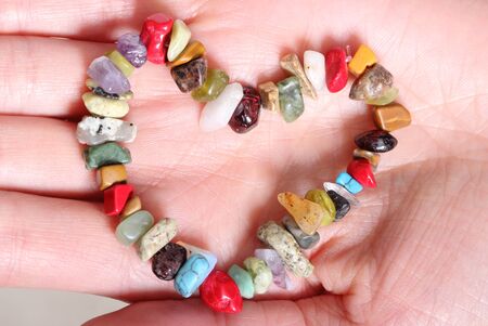Closeup of heart shaped bracelet of colored stones lying on hand of woman, valentine heart of braceletの写真素材