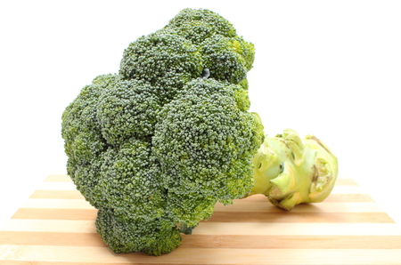 Fresh raw green whole broccoli lying on wooden cutting board  Isolated on white backgroundの写真素材