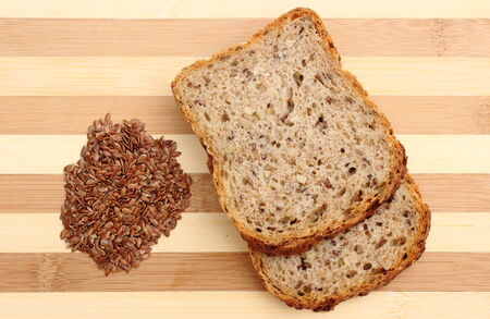Linseed on cutting board with slices of wholemeal breadの写真素材