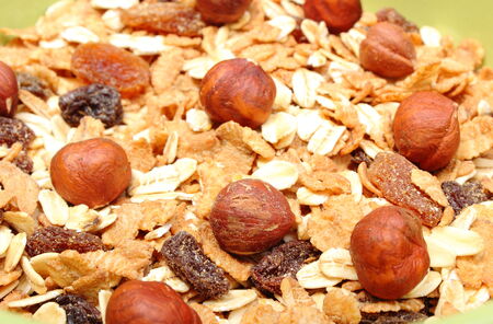 Heap of fresh muesli with hazelnut in green bowl, concept for healthy eating. Isolated on white...